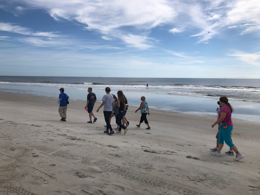 Group of people walking on a beach with the Atlantic Ocean in the background.